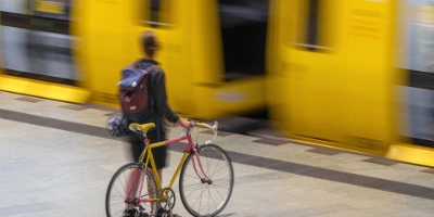 Eine Frau steht neben ihrem Fahrrad, während sie auf eine einfahrende U-Bahn wartet.